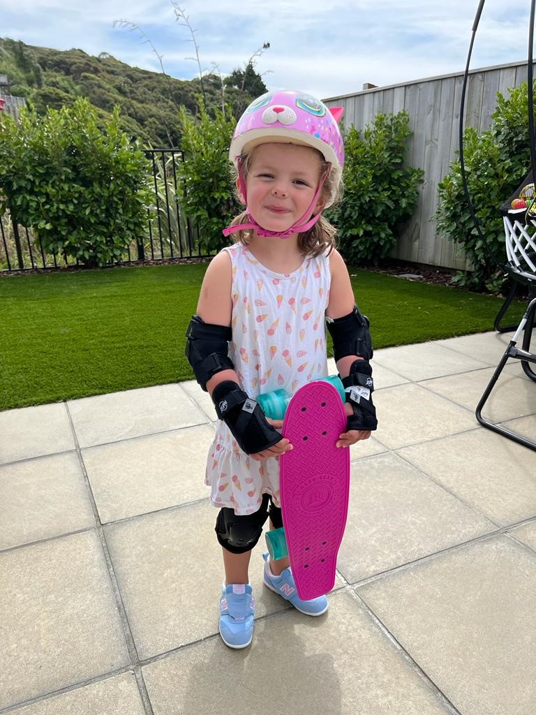 Pre-schooler Isla, in a pink helmet ready to skateboard.