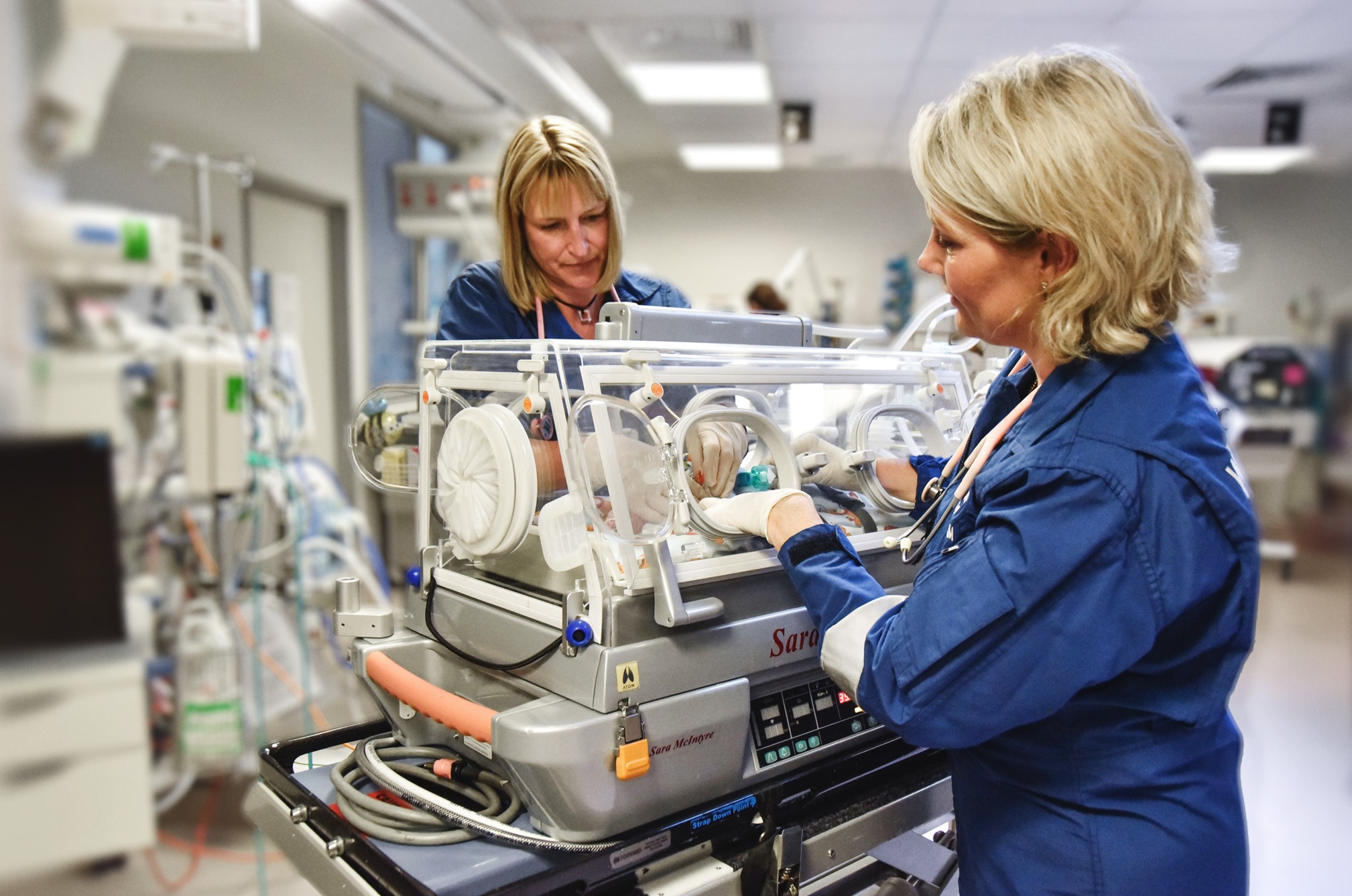 NICU flight team care for a baby in a flight transport incubator.