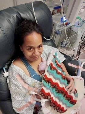 Mum sits in a chair in the NICU, cuddling her very premature baby.