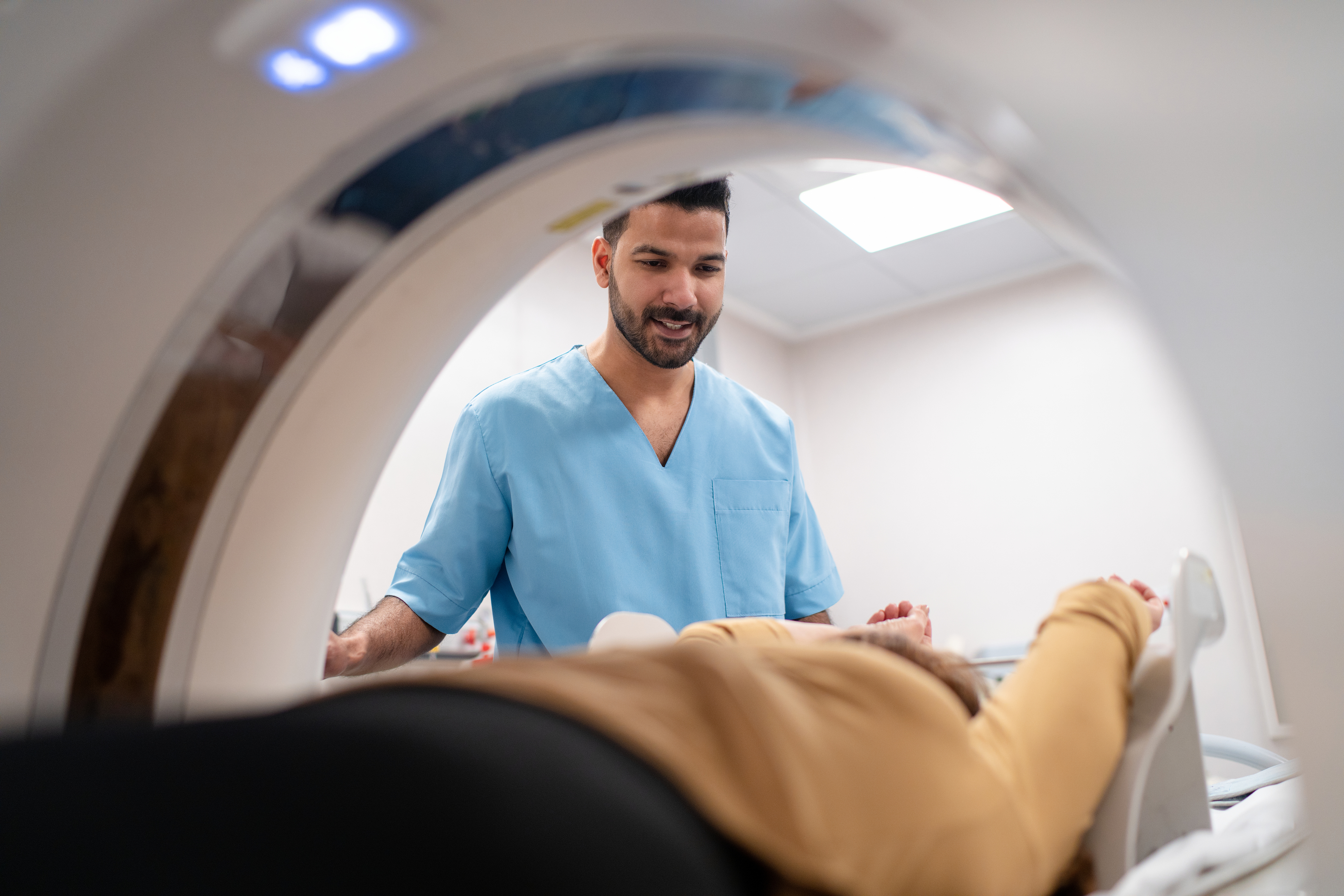 Patient lies in an MRI scanner as a smiling doctor looks on.