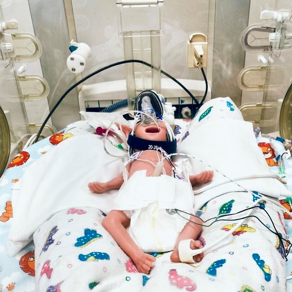 A baby medical simulation manikin hooked up to tubes.