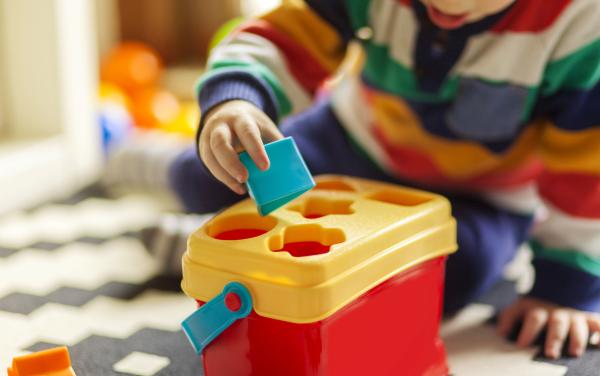 child placing blocks into a shape sorter.