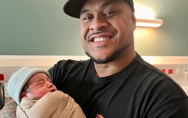 Proud Dad Villie with his new baby, wearing a merino Matariki wrap
